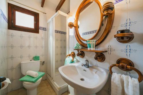 een badkamer met een wastafel, een spiegel en een toilet bij 3060 Villa Elche in Moraira