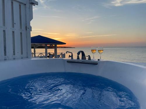 a hot tub with two glasses of wine on the beach at サンセットリゾート　かぬたん in Gushiken