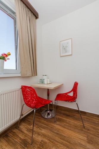 a table and two red chairs in a room at Penzion Hviezda in Bratislava