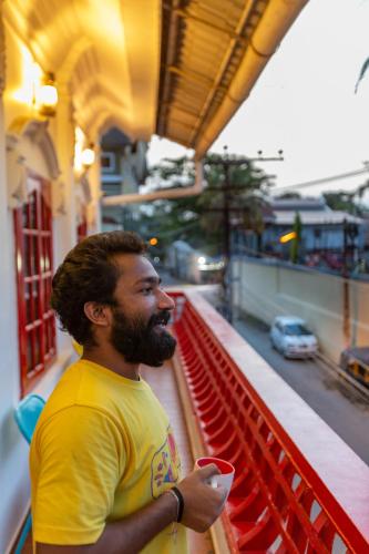 a man standing on a balcony holding a cup at goSTOPS Lite Kochi in Cochin