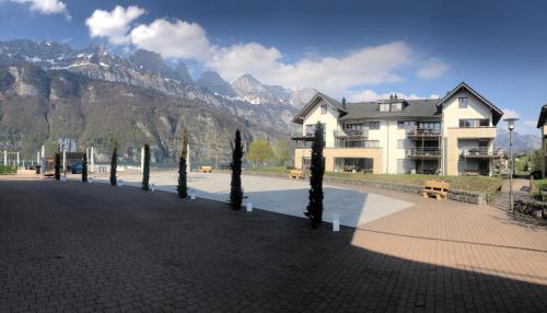 a building with a row of trees in front of a mountain at Luxuriöses Galerie-Penthouse direkt am Walensee in Unterterzen