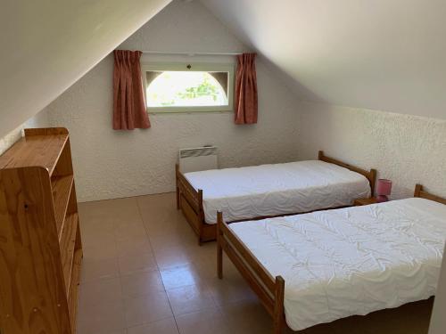 a attic room with two beds and a window at Camping Le Saillet in Lestelle-Bétharram