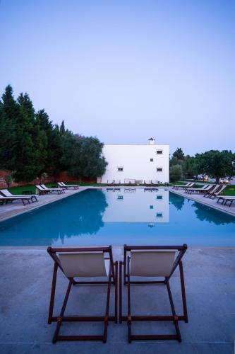 a table and chairs in front of a swimming pool at Masseria Montelauro in Otranto