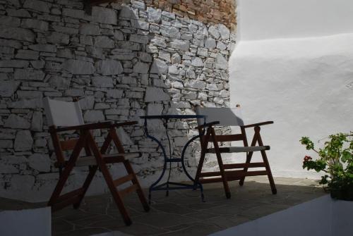 two chairs and a table in front of a stone wall at Windmill Villas in Artemonas