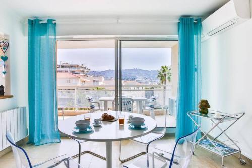 une table et des chaises dans une pièce avec une grande fenêtre dans l'établissement Bright One BDRM Apartment A/C-Swimming Pool/Congress by Olidesi, à Cannes
