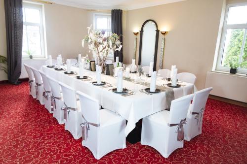 a long table in a room with white chairs at Parkhotel Diani in Leipzig
