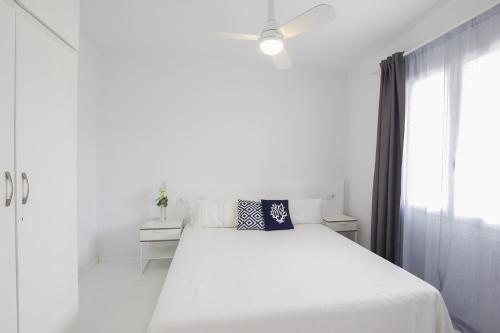 a white bedroom with a white bed and a window at Cala Galdana Apartamentos El Rio in Cala Galdana