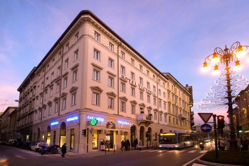 a large white building on a city street at night at Victoria Hotel Letterario in Trieste