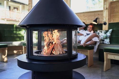a fireplace in a living room with a child in the background at Goldene Rose Karthaus a member of Small Luxury Hotels of the World in Senales
