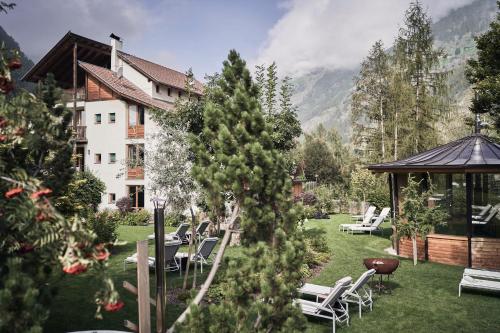 a garden with chairs and a gazebo and a building at Goldene Rose Karthaus a member of Small Luxury Hotels of the World in Senales
