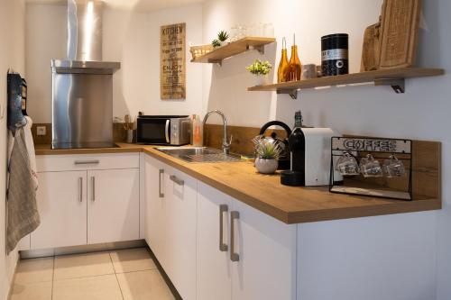 une cuisine avec des armoires blanches et un comptoir dans l'établissement La Mesange de Sarlat, à Sarlat-la-Canéda