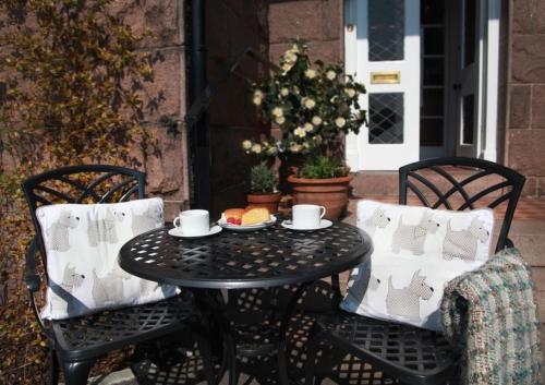 une table noire avec deux chaises et une assiette de nourriture dans l'établissement Furain, à Peterculter