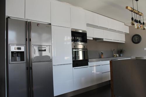 聖屈艾波爾特里厄的住宿－Les bains de mer，厨房配有白色橱柜和不锈钢冰箱