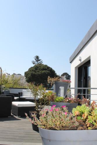 a patio with tables and potted plants on a building at Les bains de mer in Saint-Quay-Portrieux