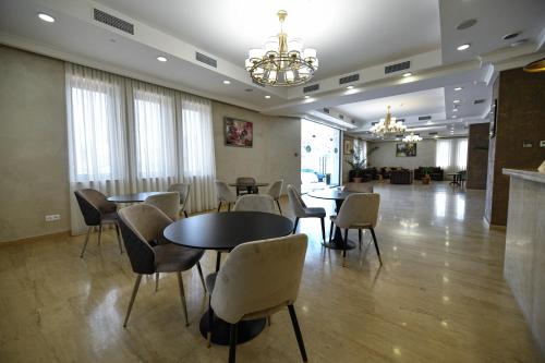 uma sala de jantar com mesas e cadeiras e um lustre em Welcome Inn Hotel em Yerevan