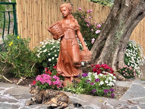 Una statua di una donna che tiene un cesto accanto a un gatto. di Foglie d'Argento a Moneglia