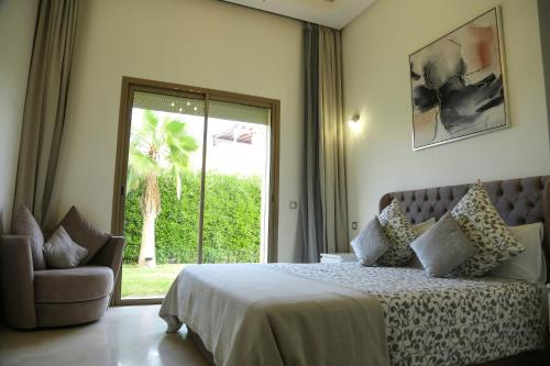 Un dormitorio con una cama y una silla y una ventana. en La Rose des Sables, en Marrakech