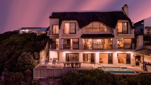 una grande casa con un tavolo di fronte di Whale Huys Luxury Oceanfront Eco Villa a Gansbaai