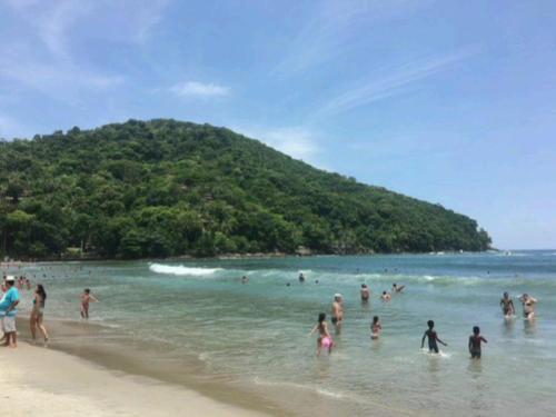 a group of people in the water at a beach at Loft Sahy - Condado Aldeia dos Reis in Mangaratiba