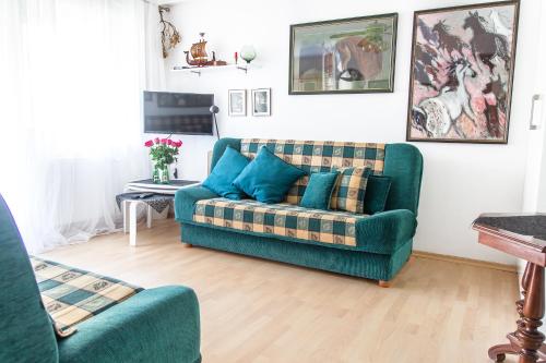 salon z zieloną kanapą i niebieskimi poduszkami w obiekcie AL-DOM apartamenty Apartament Pod Konikiem 103 w Kołobrzegu