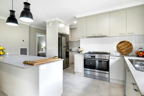 a kitchen with white cabinets and a stove at Kennedy House Euroa A delightful place to stay in Euroa