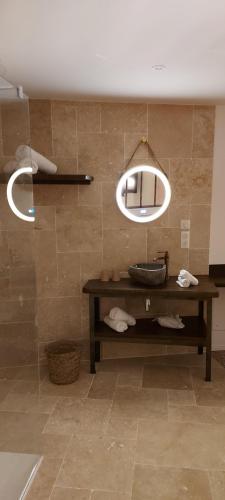 een badkamer met een tafel en een spiegel aan de muur bij auberge le petit mas in Issoire