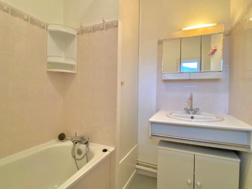 een badkamer met een wastafel, een bad en een spiegel bij REF 042 Appartement T2 avec balcon et piscine Arzon in Arzon
