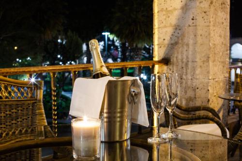 a bottle of wine in a bucket on a table with glasses at La Plaza Arequipa Hotel Boutique in Arequipa