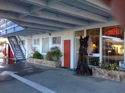 a building with a red door and a tree in front of it at Redwood Inn in Crescent City