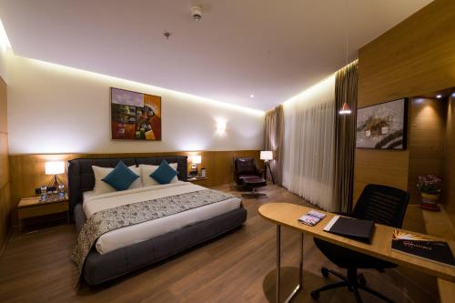 um quarto de hotel com uma cama e uma secretária em The Fern Residency, Jamnagar em Jamnagar