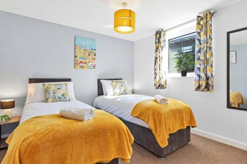 two beds in a bedroom with yellow blankets at Central Garden View -By My Getaways in Brighton & Hove