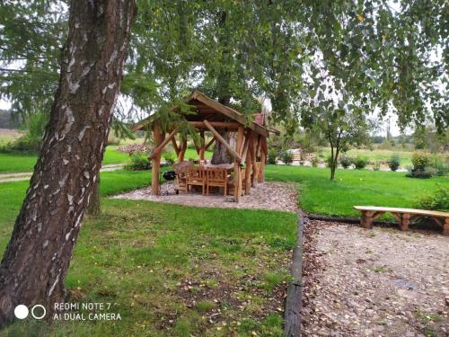 a wooden gazebo in a park with a bench at Agroturystyka "U Źródła" in Milicz