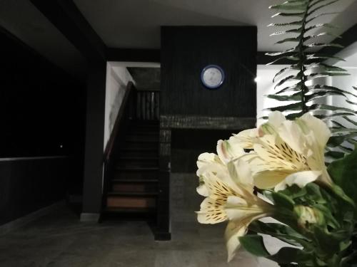 a room with a vase of flowers and a clock at Tea Mount Forest in Nuwara Eliya