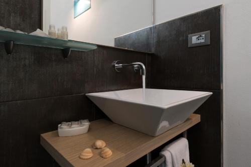 un bagno con lavandino bianco su una mensola in legno di Reef and Dream a San Vito lo Capo