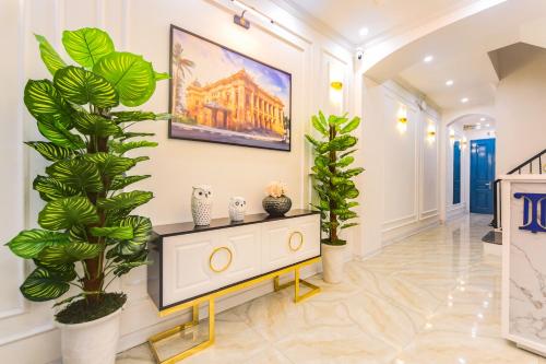 a living room with plants and a painting on the wall at Opera House Suites in Hanoi