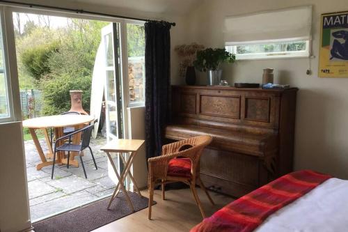 Garden Room in Hockworthy في ويلينغتون: غرفة نوم فيها بيانو وطاولة وكراسي