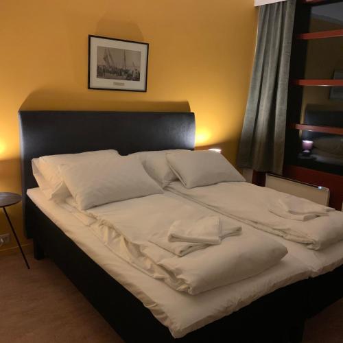 a large bed with white sheets and pillows on it at Hattfjelldal Hotell in Hattfjelldal