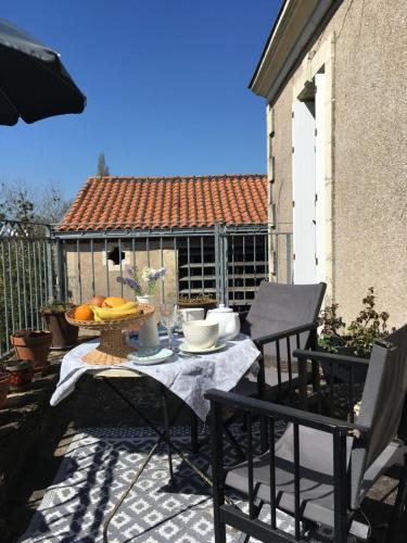 a table and chairs on a patio with food on it at La Maison Haute in La Fosse-de-Tigné