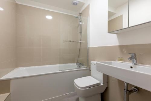 a bathroom with a tub and a toilet and a sink at Deluxe Central London Camden in London