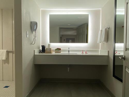 baño con lavabo y espejo grande en Days Inn by Wyndham Newnan, en Newnan