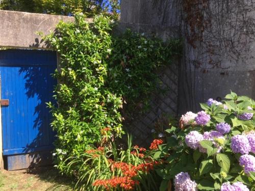 a garden with flowers next to a blue gate at Adorable Penty en pierres en bord de mer in Tréogat
