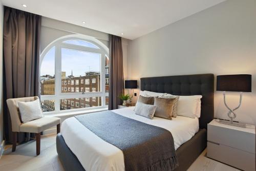 VAUXHALL BRIDGE ROAD by Q Apartments في لندن: غرفة نوم بسرير كبير ونافذة كبيرة