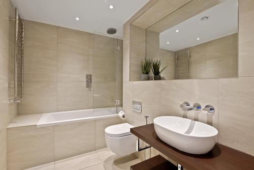 VAUXHALL BRIDGE ROAD by Q Apartments في لندن: حمام مع حوض وحوض استحمام ومرحاض