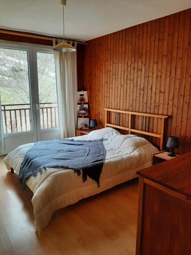 1 dormitorio con 1 cama con pared de madera en Le Veymont en Saint-Martin-en-Vercors