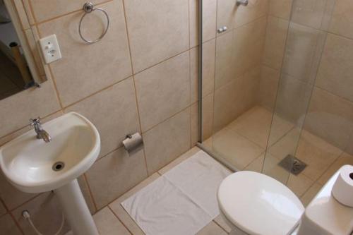 a bathroom with a shower and a toilet and a sink at Hotel Santiago in Lindóia