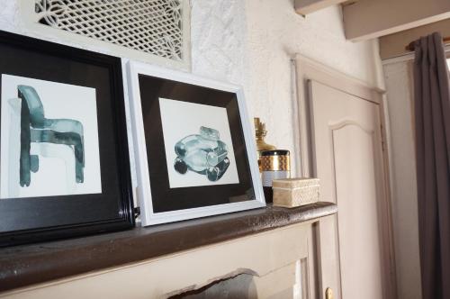 a shelf with two framed pictures on a wall at La Maison Haute in La Fosse-de-Tigné