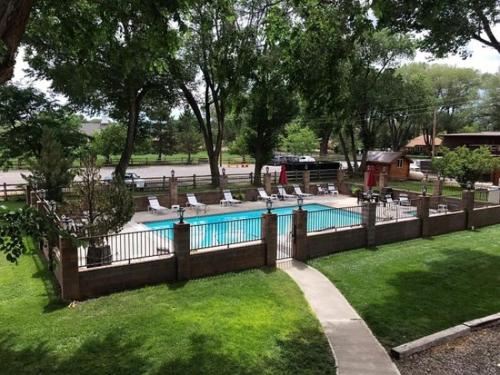 a fence around a swimming pool with chairs in a yard at Austin's Chuckwagon Motel in Torrey