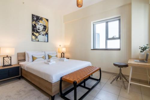 een slaapkamer met een bed, een bureau en een raam bij Business Bay Apt with Rooftop Pool, Fast WiFi, and near Burj Khalifa in Dubai