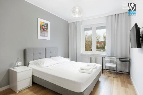 a white bedroom with a bed and a window at MS Apartments Centrum Gdyni II in Gdynia