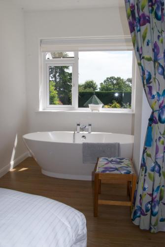 a white bathroom with a tub and a window at Malvern Holiday- Garden Flat in Great Malvern